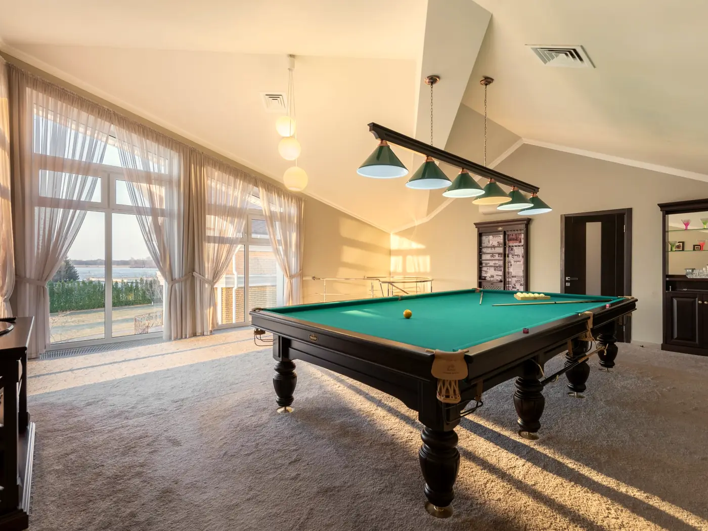 A full-size pool table under the open roof trusses of the games room