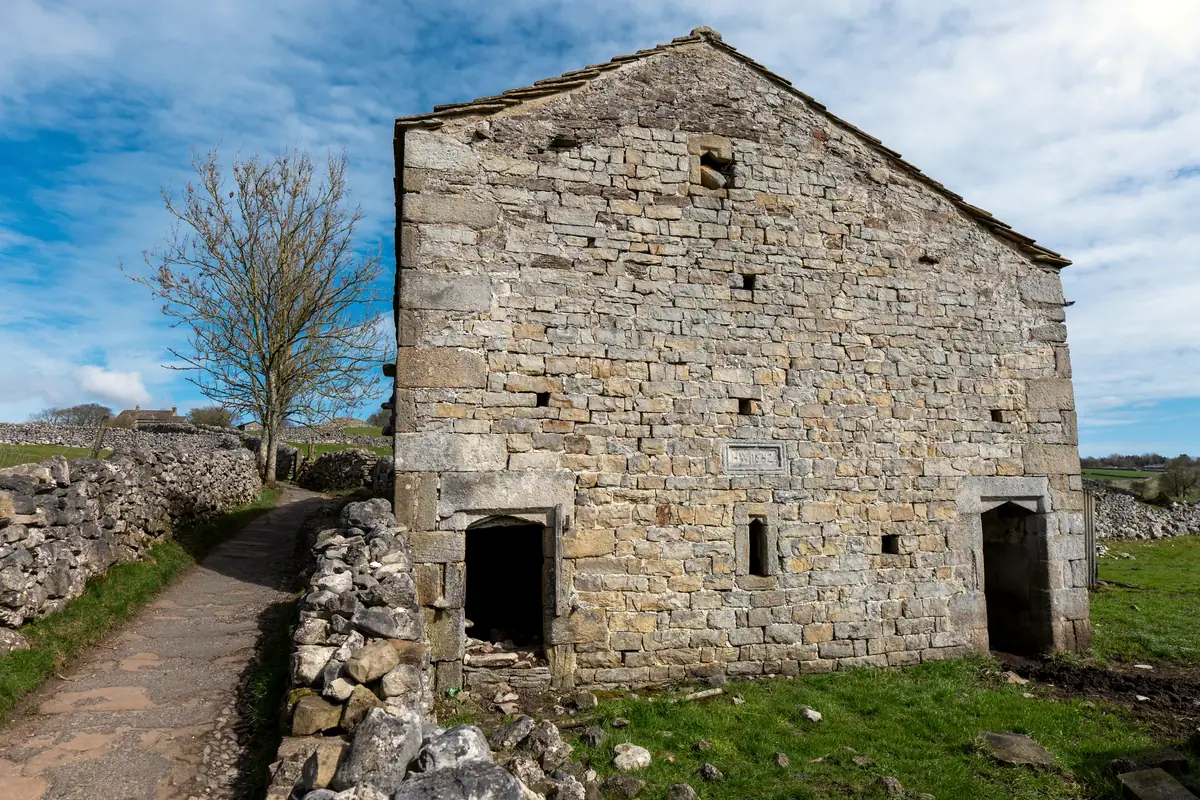 A flint barn beside a gravelled courtyard